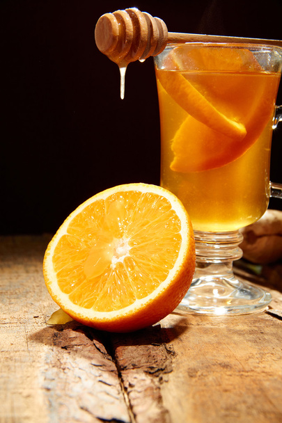 Winter tea with orange and honey on a wooden table - Фото, изображение