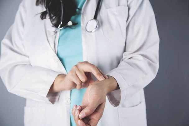 doctor woman hand in pulse on gray background - Zdjęcie, obraz