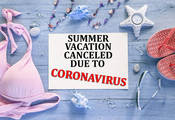  Metin içeren soyut renk arkaplanı: Coronavirüs nedeniyle yaz tatili iptal edildi. Pembe bikini, mercan taklalar, güneş gözlükleri, mavi ahşap arka plan.. - Fotoğraf, Görsel