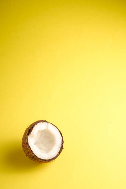 Fruta de coco único no fundo liso amarelo, conceito tropical comida abstrato, ângulo ver espaço de cópia
 - Foto, Imagem