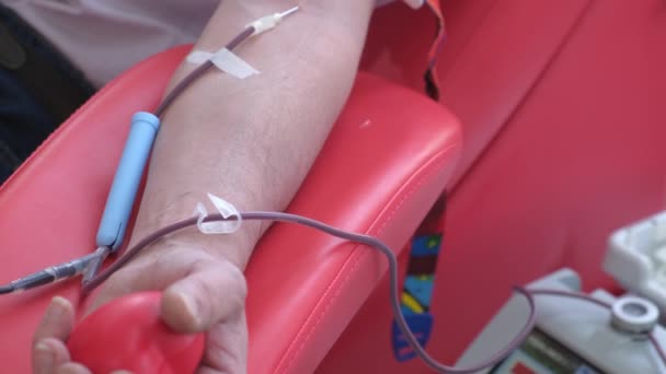 Ένα άτομο σφίγγει μια μπάλα ενώ δωρίζει αίμα σε κέντρο μετάγγισης. Αιθέριο έλαιο - Πλάνα, βίντεο