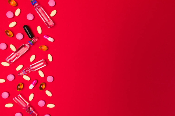 Medetsyn background from ampoules for injections, tablets and capsules on a red background. Copy space. - Foto, Bild