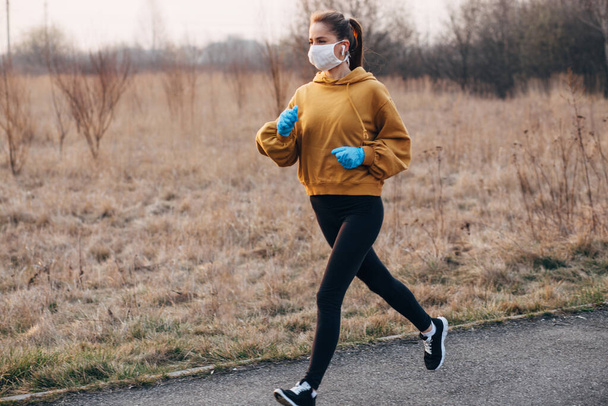 COVID-19 Пандемическая коронавирусная девочка в маске и синих перчатках во время карантина вышла на пробежку
 - Фото, изображение