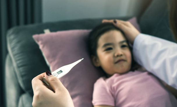 Azjatycka pediatra używa termometru do pomiaru gorączki u dzieci - Zdjęcie, obraz