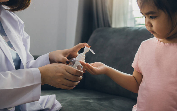 Pediatra fêmea está segurando uma garrafa de álcool gel higienizador de mão para lavar as mãos matar germes e bactérias para as crianças durante o surto de coronavírus
. - Foto, Imagem