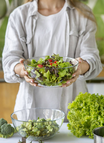 Mulher irreconhecível fazendo salada fresca na cozinha
 - Foto, Imagem