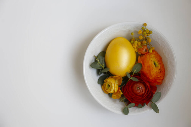 Easter table setting foristic composition with traditional golden painted egg, beautiful tableware on plain white table. Top view, copy space, close up, isolated background. - Foto, afbeelding