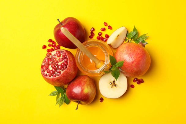 Appel, honing en granaatappel op gele achtergrond, bovenaanzicht - Foto, afbeelding