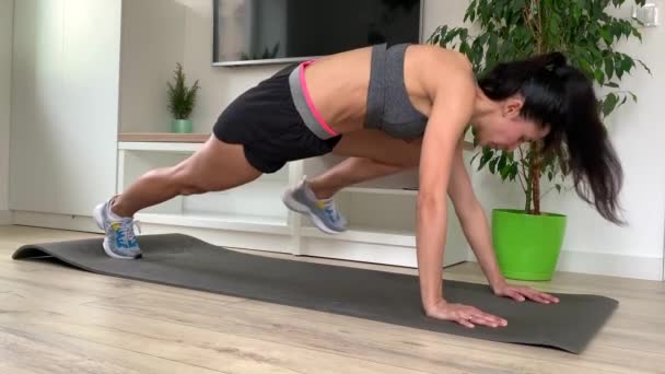 Young Fitness Woman In Sportswear Doing Plank Exercise At Home Or In Studio. Dynapic plank during quarantine. Exercises for working out the stomach muscles - Footage, Video