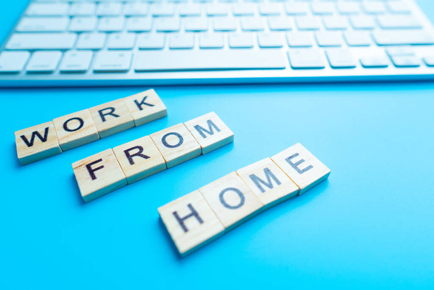 Rozmazané pozadí, dřevěné desky, umístění počítače s textem WORK FROM HOME. Společnost umožňuje zaměstnancům pracovat z domova, aby se vyhnuli virům. - Fotografie, Obrázek