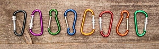 panoramic shot of colorful carabiners on wooden table - Photo, Image