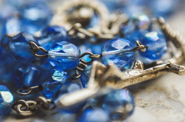 closeup of a metal cross with jesus blue glass rosary convoluted - Photo, Image