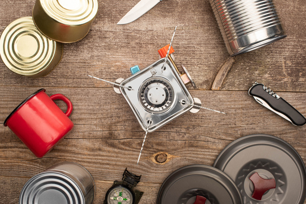 top view of gas burner, tin cans, metal cup,  on wooden table - Photo, Image