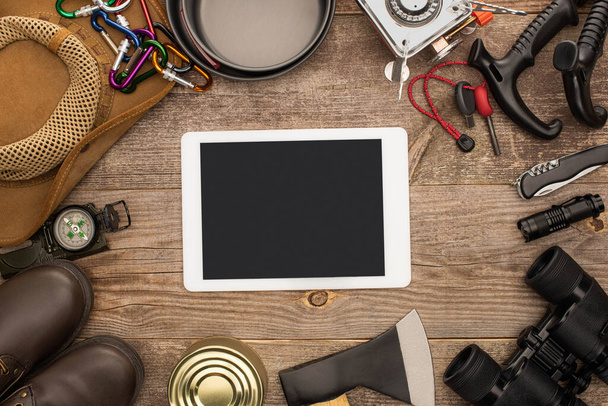 top view digitális tabletta fekete képernyővel a közelben túrázó berendezés fa asztalon - Fotó, kép