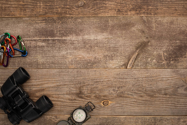 Ansicht von Karabiner, Fernglas und Kompass auf Holztisch - Foto, Bild