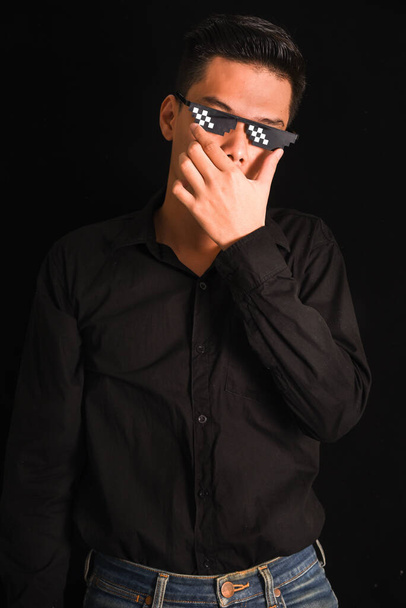 Пристойний молодий чоловік у чорній сорочці, який тримає руки схрещеними, носить окуляри на чорному тлі, Азіатський портрет. - Фото, зображення