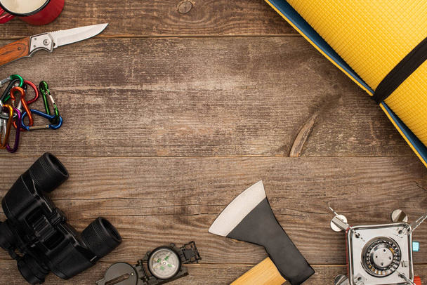 Draufsicht auf gelbe Rollmatte und Wanderausrüstung auf Holztisch - Foto, Bild
