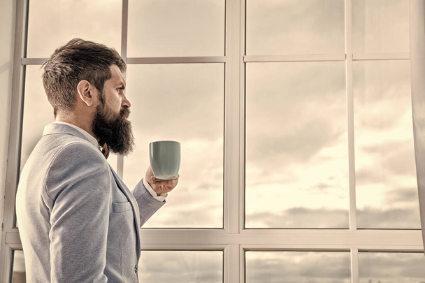 His big day. Wedding morning concept. Wedding day. Groom bearded hipster man wear blue tuxedo and bow tie. Man stand at window nervous about wedding. Life choices and expectations. But first coffee - Foto, afbeelding