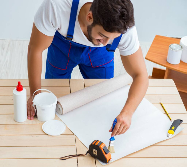 Travailleur travaillant sur papier peint pendant la rénovation - Photo, image