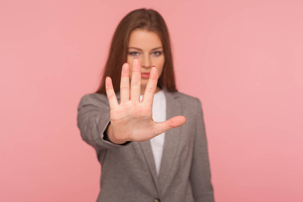 Stop, access prohibited! Portrait of strict lady boss in business suit standing with outstretched hand, making warning expression, denial forbiddance concept. studio shot isolated on pink background - Foto, Bild