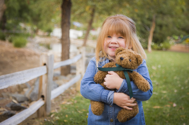 мила усміхнена молода дівчина husting її Teddy Bear зовні
 - Фото, зображення