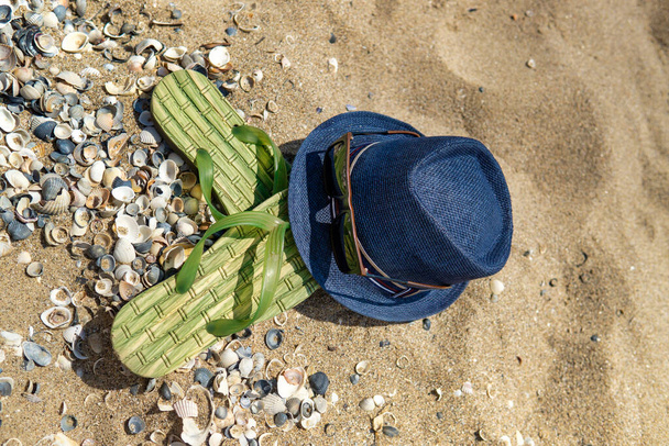 Accesorios para la playa tumbado en la arena, zapatillas de hombre y gafas de sol en la arena de la playa
 - Foto, imagen