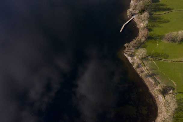 イングランド湖地区のコンストン湖の多くの小さな湾の一つのドローンショット - 写真・画像