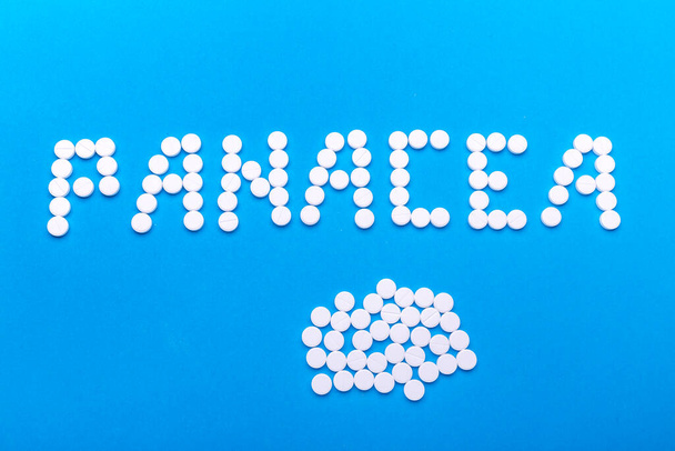 A inscrição Panacea feito de pílulas em um fundo azul
 - Foto, Imagem