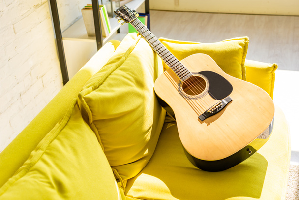 close up of acoustic guitar on yellow sofa in sunlight - Φωτογραφία, εικόνα