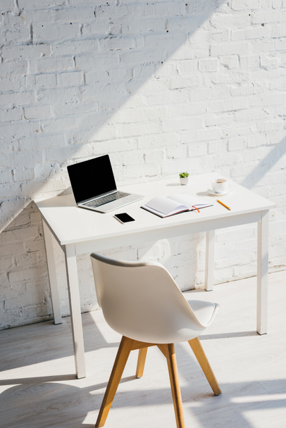 escritório em casa com laptop, smartphone, café e cadeira à luz do sol
 - Foto, Imagem