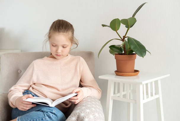 Young teenager girl reading book at home. Distance education, home education. Self isolation concept - Image - Valokuva, kuva
