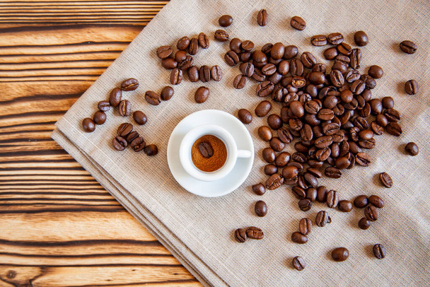 Small cup with coffee beans on the wood table. - Foto, Imagem