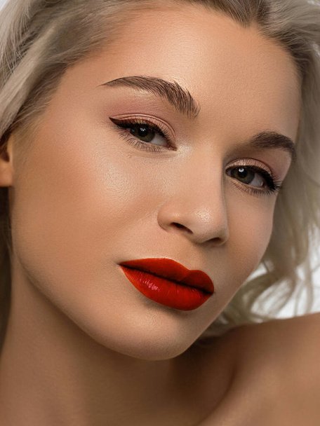 Closeup portrait of a woman with developing straight hair. Sweet tender young girl blonde. Red lipstick, transparent clean skin. Skin care natural cosmetics in the spa salon or cosmetology. - Photo, Image
