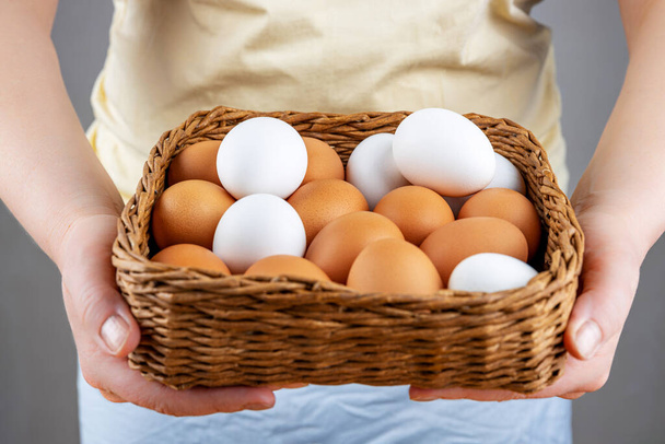 Female hands hold a basket of fresh chicken eggs, close-up, selective focus, shallow depth of field. The concept of healthy food, spring religious holidays. - Фото, зображення