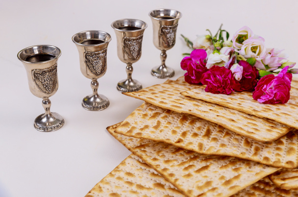Pane ebraico matzah su sfondo rustico in legno con quattro coppe di vino e fiori. Concetto vacanza Pasqua
 - Foto, immagini