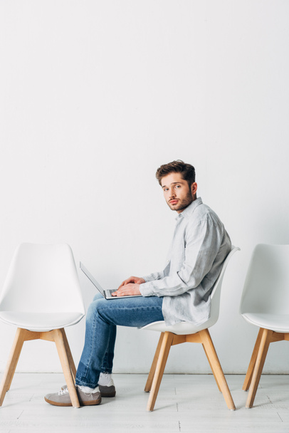Oldalnézet férfi laptoppal ül a széken, miközben várja az állásinterjút - Fotó, kép