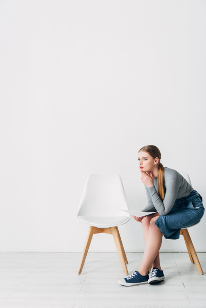 Oldalnézet a nő önéletrajzával néz félre a széken az irodában  - Fotó, kép