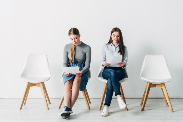 Jeunes femmes avec CV assis sur des chaises dans le bureau
  - Photo, image