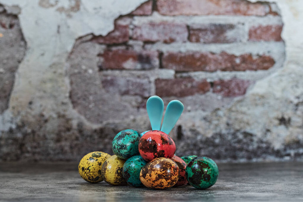 Щасливого Великодня, перо намальовано плямисті яйця в дерев'яній чаші на синьому бетонному фоні і вухах кроликів, символ весняного православного і католицького свята.. - Фото, зображення