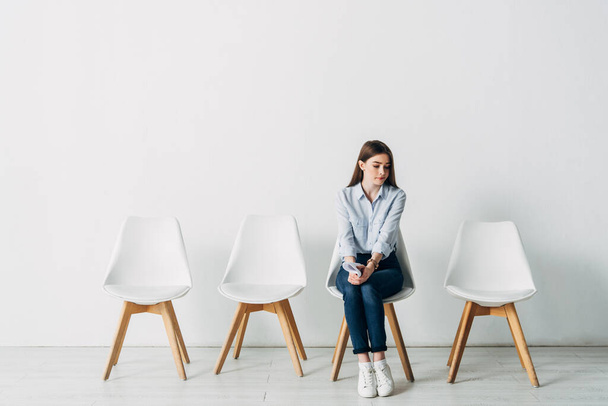 Gyönyörű alkalmazott önéletrajzzal ül a széken az irodában  - Fotó, kép