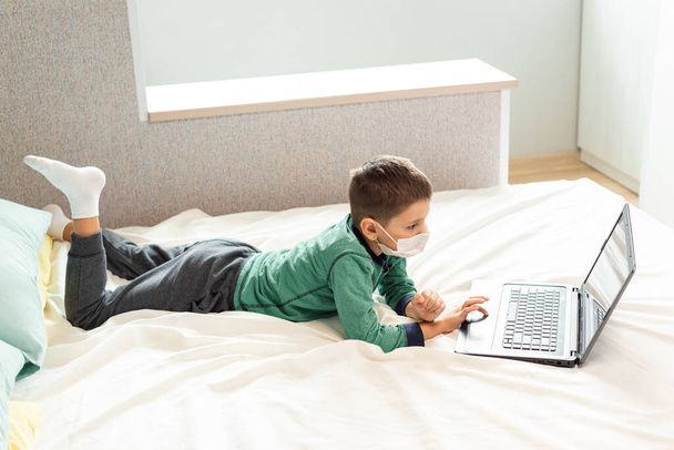 Залишайтеся вдома, щоб запобігти пандемії коронавірусу. Дитина навчається онлайн на ноутбуці під час карантину. Дистанційне навчання. Профілактика епідемії. COVID-19
. - Фото, зображення