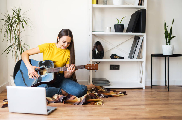 Een vrouw kijkt video tutorial op gitaar spelen - Foto, afbeelding