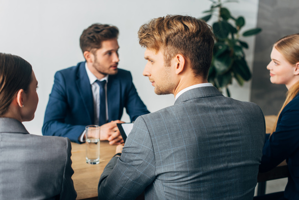 Enfoque selectivo de los reclutadores mirándose entre sí durante la entrevista de trabajo con el empleado
  - Foto, Imagen