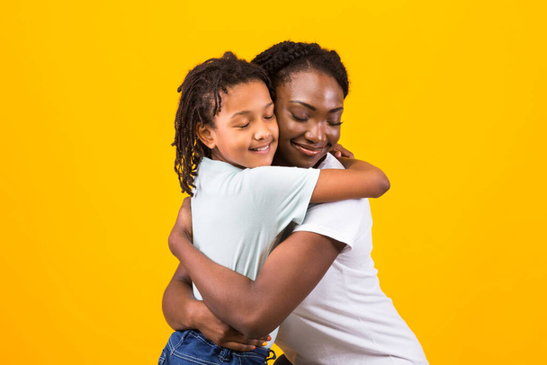 Schwarze Mutter umarmt ihr glückliches Mädchen - Foto, Bild