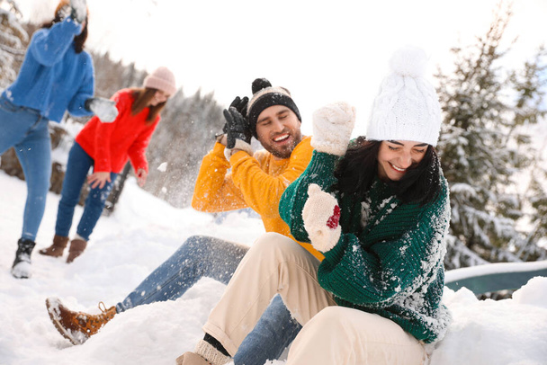 Group of friends playing snowballs outdoors. Winter vacation - 写真・画像