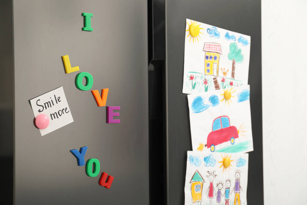 Modern refrigerator with child's drawings, note and magnets, closeup - Foto, afbeelding