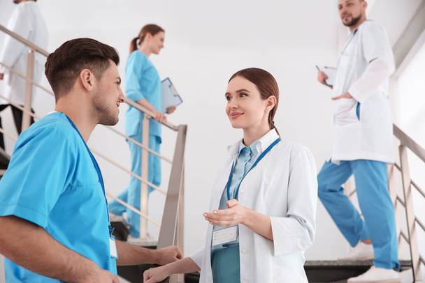 Female doctor talking to colleague on staircase in clinic - Foto, imagen