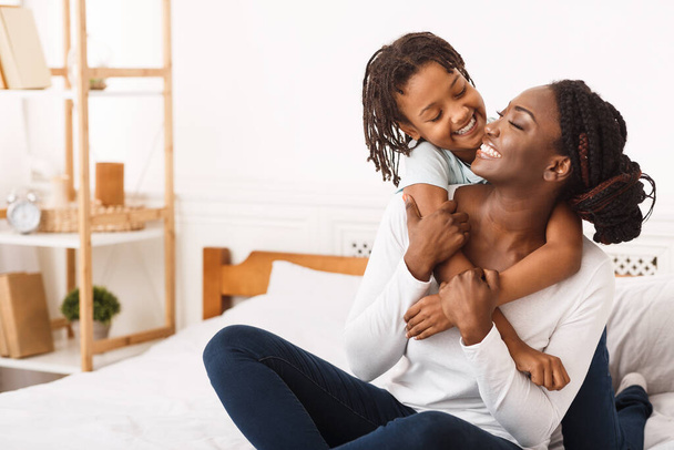 Schwarzes Mädchen umarmt ihre Mutter zu Hause - Foto, Bild