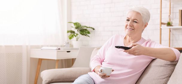 Vanhempi nainen katsomassa televisiota sepelvaltimoviruksen eristyksen aikana kotona
 - Valokuva, kuva
