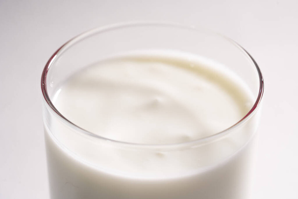 Vaso de yogur vegetariano fresco sobre leche de coco. Leche ecológica en un vaso transparente sobre fondo blanco, aislada
 - Foto, imagen